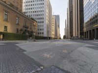 an empty city street with tall buildings and cars parked in the middle of the road