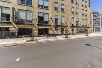 an empty street surrounded by tall buildings and fire escapes in the background with people sitting outside