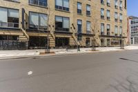 an empty street surrounded by tall buildings and fire escapes in the background with people sitting outside