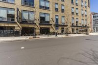 an empty street surrounded by tall buildings and fire escapes in the background with people sitting outside