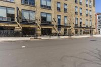 an empty street surrounded by tall buildings and fire escapes in the background with people sitting outside