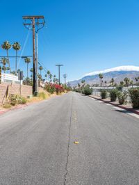 empty street lined with telephone poles and a mountains in the distance in palm springs, california