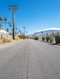 empty street lined with telephone poles and a mountains in the distance in palm springs, california