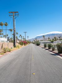 empty street lined with telephone poles and a mountains in the distance in palm springs, california