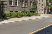 an empty street next to buildings with plants and flowers in the corner of the road