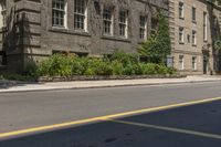 an empty street next to buildings with plants and flowers in the corner of the road