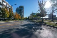 a empty street is shown with buildings and some trees in the background during autumn time