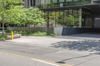 an empty street next to tall glass buildings and trees in front of a city building