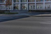 an empty street near a building with some cars parked on the sidewalk in front of it