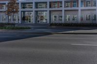 an empty street near a building with some cars parked on the sidewalk in front of it