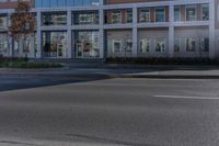 an empty street near a building with some cars parked on the sidewalk in front of it