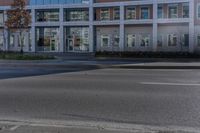 an empty street near a building with some cars parked on the sidewalk in front of it