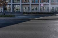 an empty street near a building with some cars parked on the sidewalk in front of it