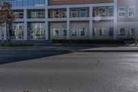 an empty street near a building with some cars parked on the sidewalk in front of it