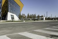 an empty street with no cars on it near a building that has some windows in the sides