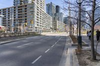 empty street with high rise building in background with pedestrians walking by in the foreground