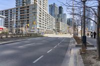 empty street with high rise building in background with pedestrians walking by in the foreground