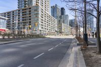 empty street with high rise building in background with pedestrians walking by in the foreground