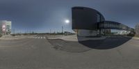 a 360 lens picture of the sun and building of an empty street with some people