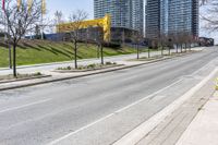 empty street in a city with high rise building behind it, and construction equipment laying on the side of the road