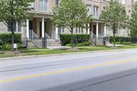 an empty street next to a row of townhouses, one that is standing in front of a fence