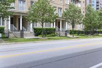 an empty street next to a row of townhouses, one that is standing in front of a fence