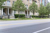 an empty street next to a row of townhouses, one that is standing in front of a fence