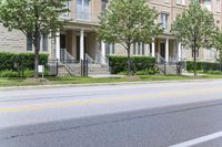 an empty street next to a row of townhouses, one that is standing in front of a fence