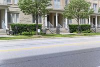 an empty street next to a row of townhouses, one that is standing in front of a fence