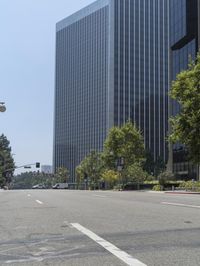 this is a street that is empty and has many trees on it as well as some skyscrapers