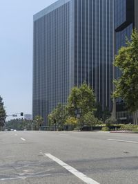 this is a street that is empty and has many trees on it as well as some skyscrapers