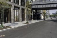 an empty street under a bridge that connects two buildings to the sidewalk and a sidewalk