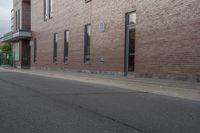 an empty street next to an apartment building with tall windows in front of it and a red fire hydrant on one side and an open door