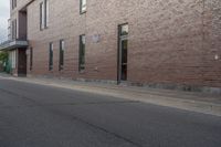 an empty street next to an apartment building with tall windows in front of it and a red fire hydrant on one side and an open door