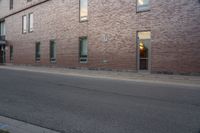 an empty street next to an apartment building with tall windows in front of it and a red fire hydrant on one side and an open door