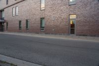 an empty street next to an apartment building with tall windows in front of it and a red fire hydrant on one side and an open door