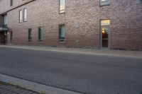 an empty street next to an apartment building with tall windows in front of it and a red fire hydrant on one side and an open door