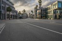 an empty street lined with buildings and palm trees on either side of the road is a crosswalk,