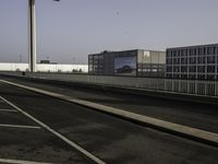 an empty street, two empty parking spaces next to an empty warehouse building with a large advertisement on the side of it