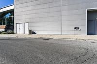an empty street with a white wall near an industrial building and a street sign for the number 50