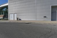 an empty street with a white wall near an industrial building and a street sign for the number 50