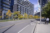 a empty street is pictured with many trees in the foreground and a man riding a bike