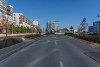 an empty street with buildings and some trees in the background and a blue sky behind