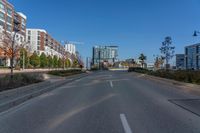 an empty street with buildings and some trees in the background and a blue sky behind