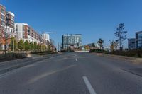 an empty street with buildings and some trees in the background and a blue sky behind