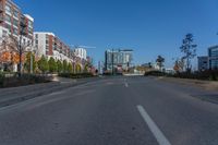 an empty street with buildings and some trees in the background and a blue sky behind