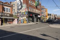 a street is littered with graffiti painted stores and small businesses that are vacant and empty