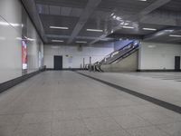 an empty subway with multiple steps down and no people around it as well as a banner about how to go