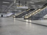 an empty subway with multiple steps down and no people around it as well as a banner about how to go