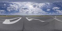 a large empty tarmac with arrows pointing in different directions and white writing on it